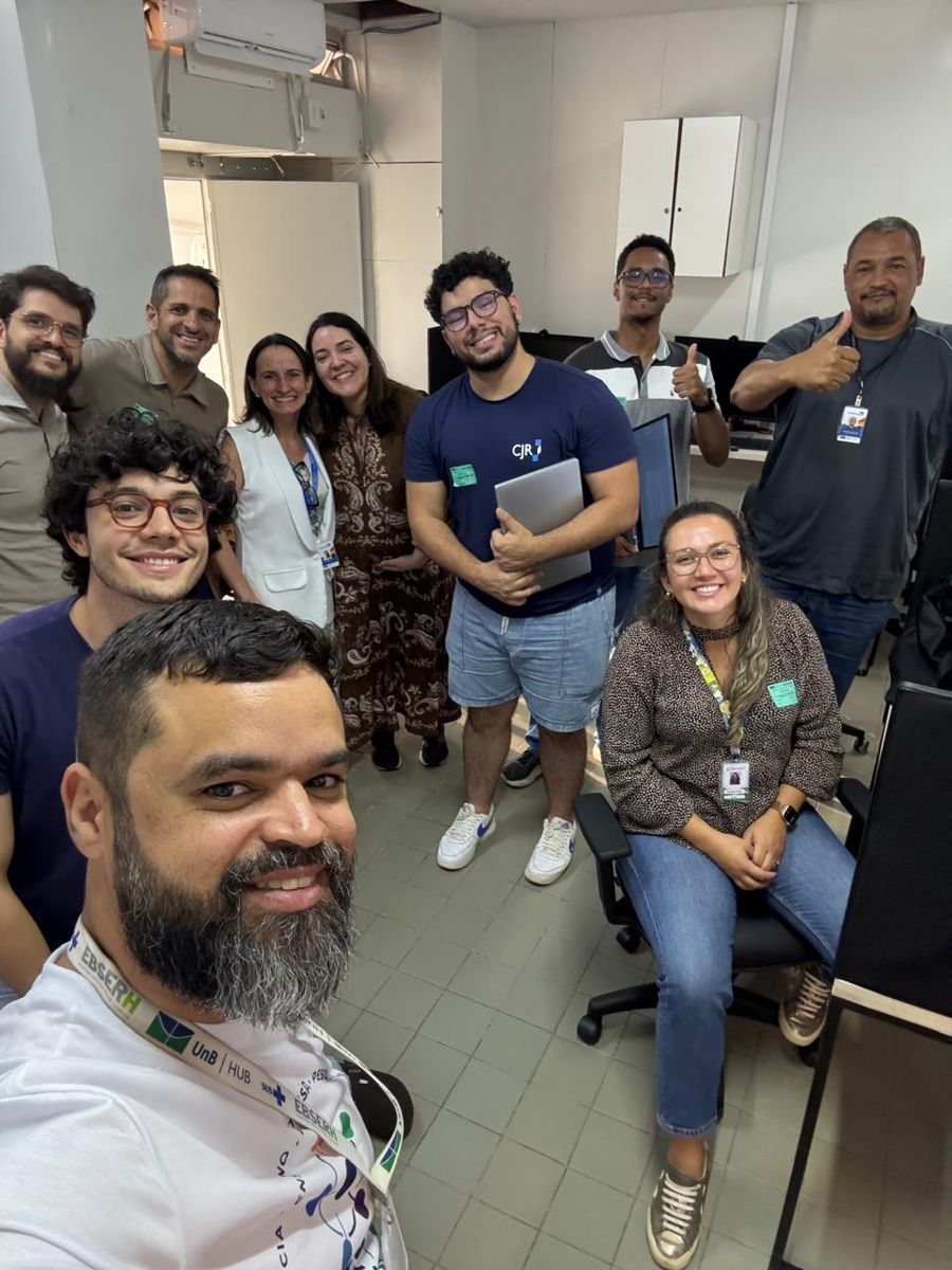 Selfie em grupo de participantes e integrantes do GT 12 sorrindo no laboratório da oficina.