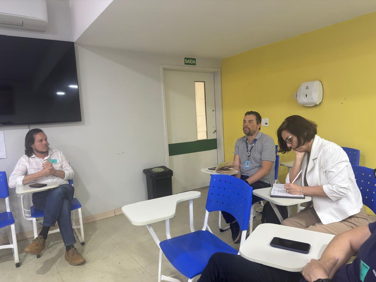 Integrantes do GT 12 conversam sentados em carteiras durante trabalho em grupo.